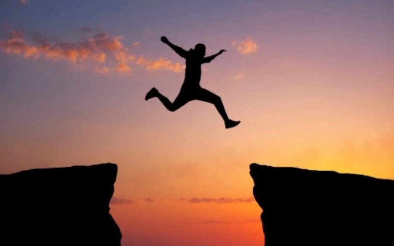 Website pillar content header person jumping across a chasm